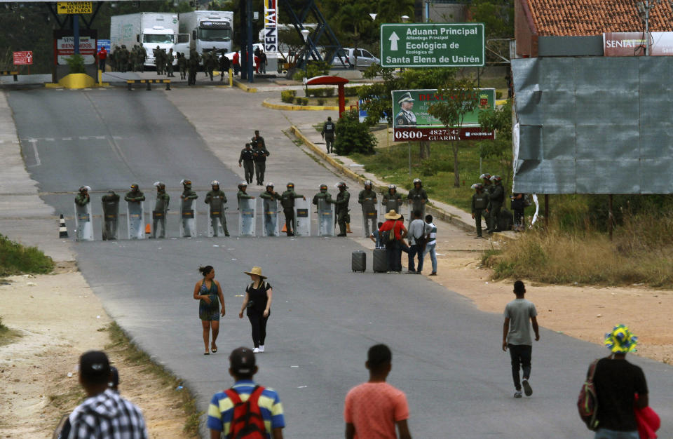 Venezuelan national guards block a road at the border between Brazil-Venezuela, in Pacaraima, Roraima state, Brazil, Friday, Feb. 22, 2019. Heightened tensions in Venezuela left a woman dead and a dozen injured near the border with Brazil on Friday, in the first deadly clash over the opposition's attempts to bring in emergency food and medicine that President Nicolas Maduro says isn't needed and has vowed to block. (AP Photo/Edmar Barros)