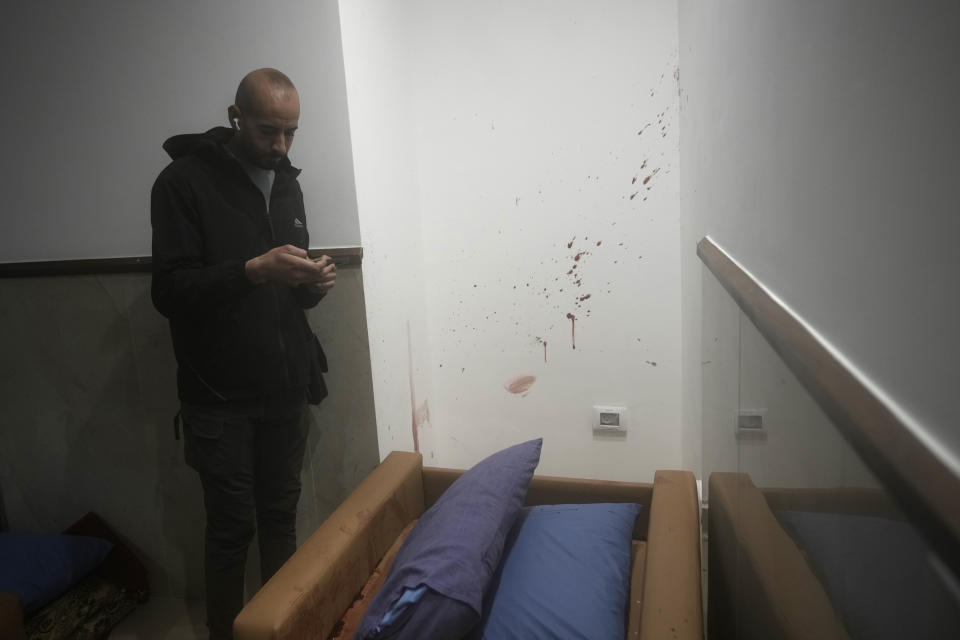 A Palestinian films blood stains in a room at Ibn Sina Hospital following a deadly Israeli military raid in the West Bank town of Jenin, Tuesday, Jan. 30, 2024. Armed Israeli undercover forces disguised as women and medical workers stormed the hospital on Tuesday, killing three Palestinian militants. The Palestinian Health Ministry condemned the incursion on a hospital, where the military said the militants were hiding out. (AP Photo/Majdi Mohammed)