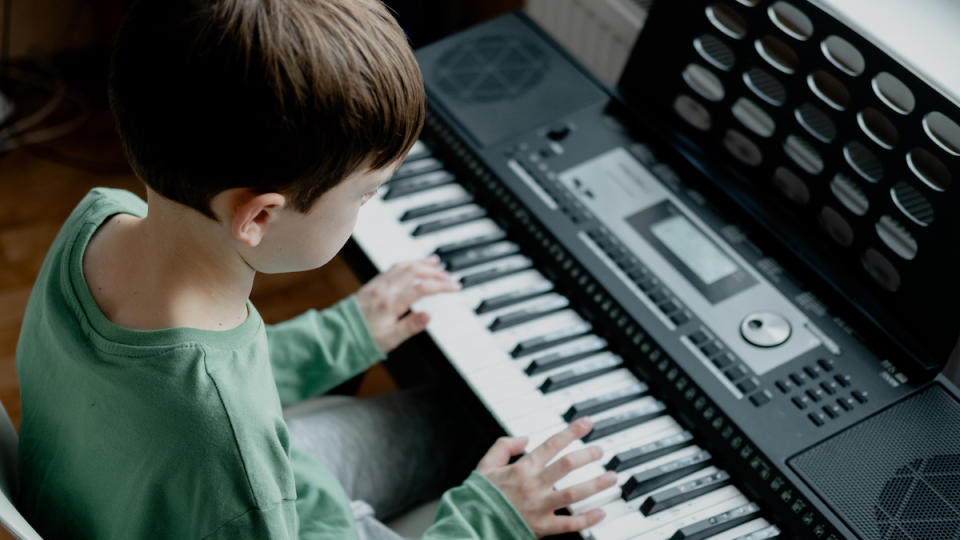 A boy with brown hair playing the keyboard