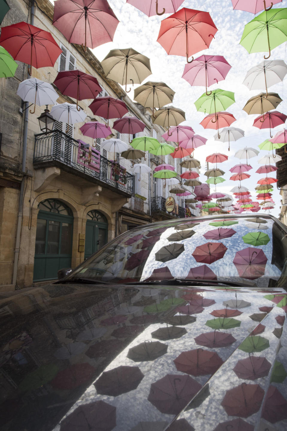 <p>Umbrellas hang above the street as part of an art installation called 'Relooker ma rue’ meaning ‘refresh my road’ in Sainte-Foy-La-Grande, France. The decorations are organised by local businesses to make the streets look more cheerful over the summer period. (James D. Morgan/Getty Images)<br></p>