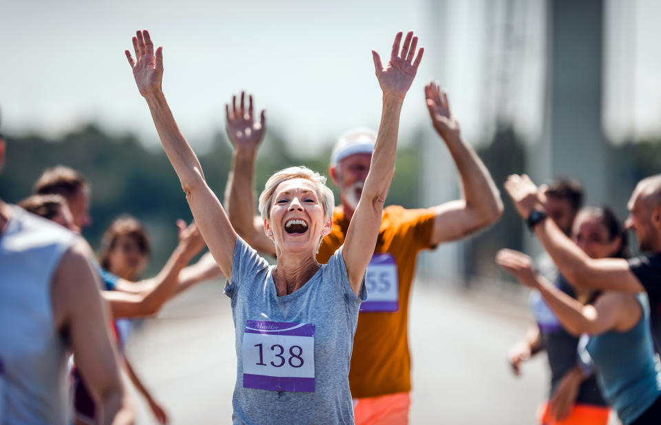 Older woman successfully finishing a marathon. (Getty Images)