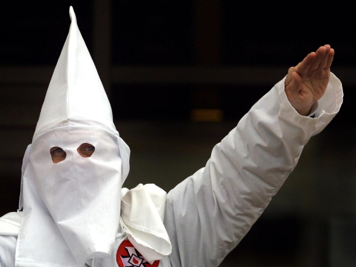 A Klansman raises arm during a “white power” chant at a KKK rally in 2000 (Getty Images)