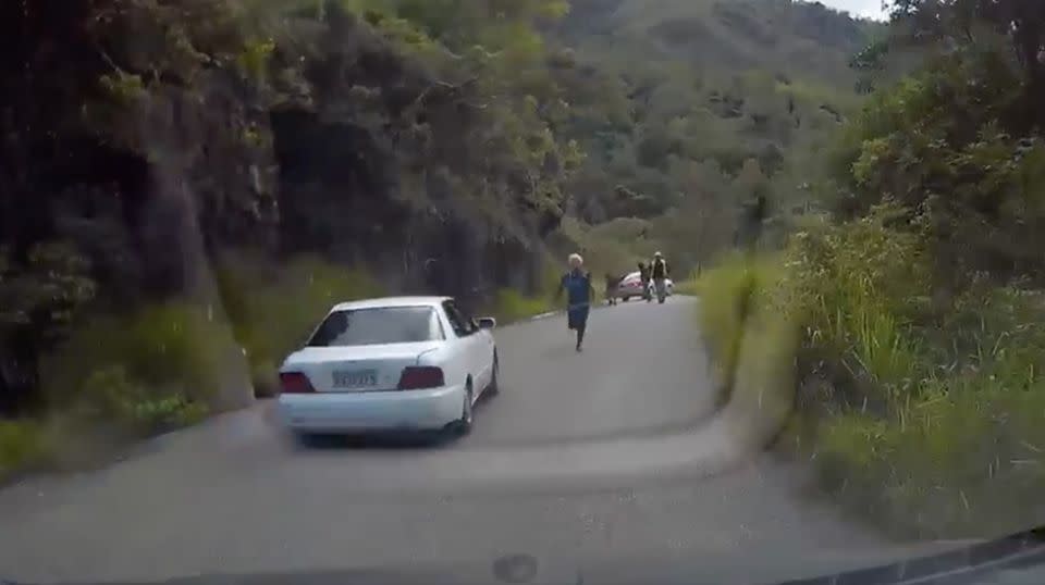 One man can be seen desperately giving chase as the Australian father speeds at reverse back up the steep and windy mountain. Source: Facebook