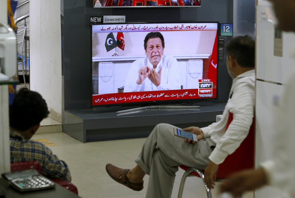 People listen the speech of Pakistani politician Imran Khan, chief of Pakistan Tehreek-e-Insaf party, telecasting on news channels at a shop in Islamabad, Pakistan, Thursday, July 26, 2018. Khan declared victory Thursday for his party in the country's general elections, promising a "new" Pakistan following a vote that was marred by allegations of fraud and militant violence. (AP Photo/Anjum Naveed)