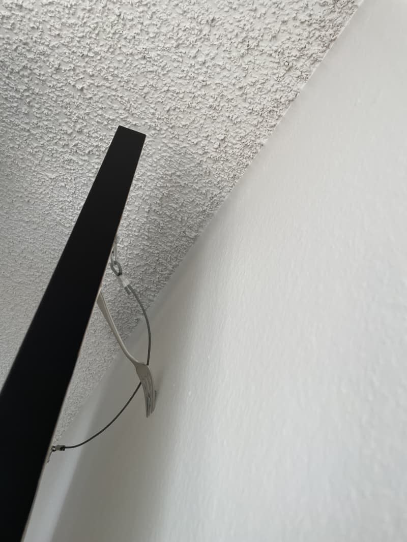 Sliding the wire of a picture frame over a fork that's held up by a nail in the wall