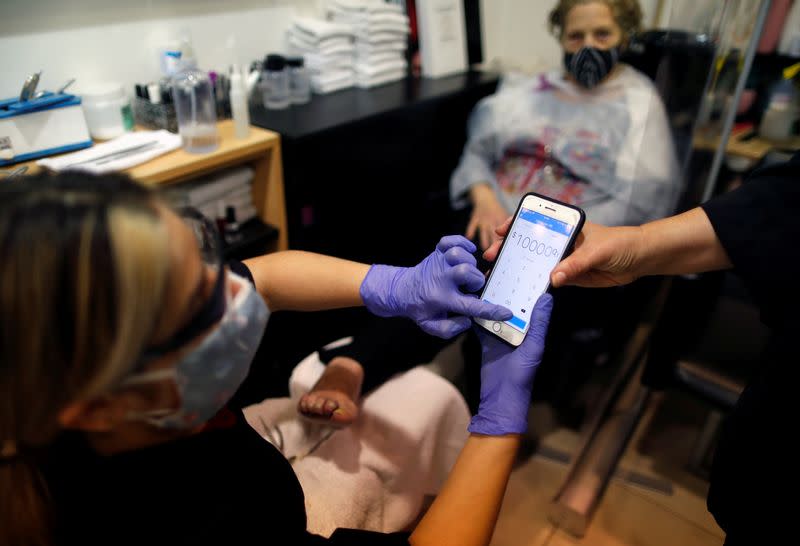 AM hair salon owner, Andrea Manoli, asks for help to use Mercado Pago app to an employee, at her store in Buenos Aires