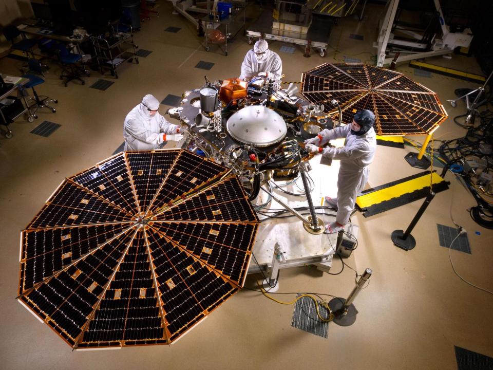 insight lander space science platform robot with two octagon solar arrays deployed inside clean room with technicians