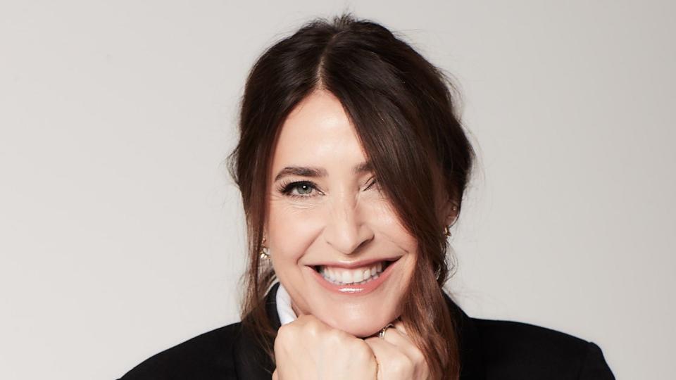 Lisa Snowdon smiling in a black blazer and a white short