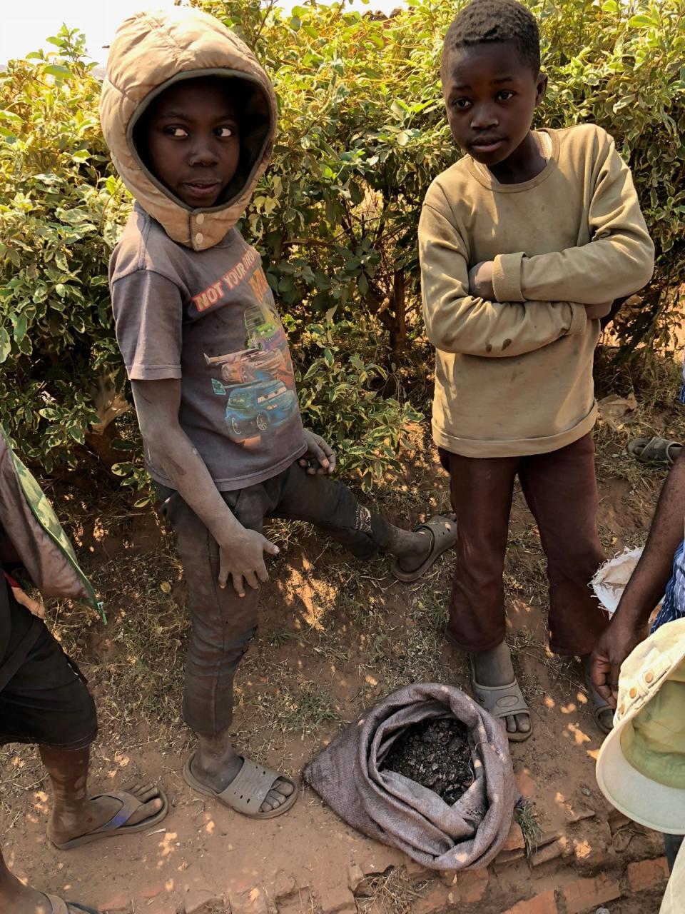 Two boys stand over their sack of scraps of cobalt. Thousands of children are mining for cobalt in the DRC as their families cannot afford to pay school fees on meagre wages (Siddharth Kara)