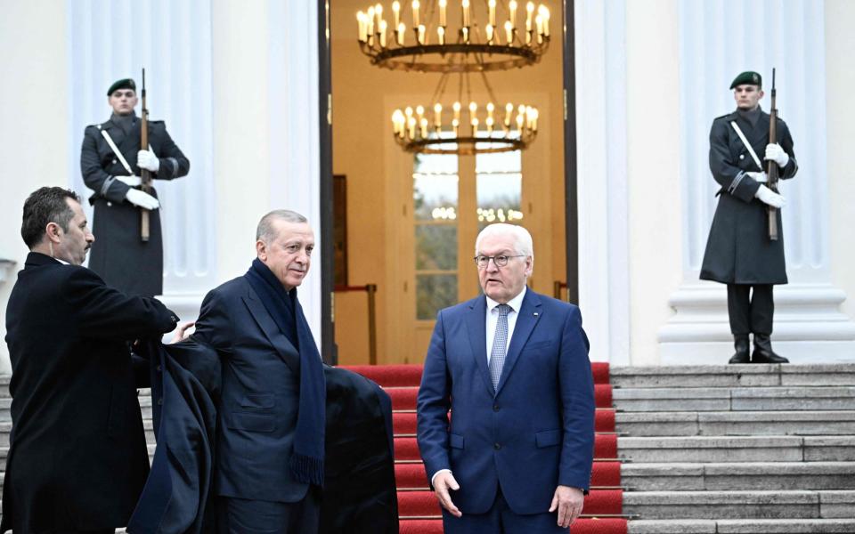 Turkish President Recep Tayyip Erdogan (C) is helped out of his coat as German President Frank-Walter Steinmeier (R) waits to welcome him for his visit at Bellevue presidential palace in Berlin on November 17, 2023. German leaders host Turkey's President Recep Tayyip Erdogan for talks on November 17, 2023, in a highly controversial visit made more explosive by Erdogan's branding of Israel as a "terror state". (Photo by Tobias SCHWARZ / AFP) (Photo by TOBIAS SCHWARZ/AFP via Getty Images)