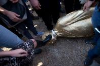 <p>Eine Frau tritt in Tel Aviv auf den Kopf einer goldenen Statue des israelischen Premierministers Benjamin Netanyahu. (Bild: AP Photo/Oded Balilty) </p>