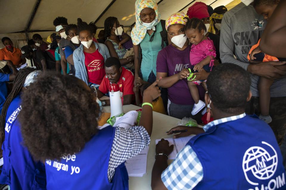 Haitians who were deported from the U.S. border with Mexico are attended by members of the IOM UN Migration organization before they get tested for COVID-19 at Toussaint Louverture International Airport in Port-au-Prince, Haiti, Monday, Sept. 20, 2021. The U.S. is flying Haitians camped in a Texas border town back to their homeland. (AP Photo/Rodrigo Abd)