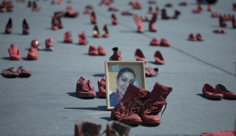 Un retrato de Eugenia Machuca Campos es colocado al lado de unas botas para mujer entre numeroso calzado femenino pintado de rojo durante una protesta contra los feminicidios efectuada en la plaza del Zócalo, en el centro de la Ciudad de México, el sábado 11 de enero de 2020. (AP Foto/Christian Palma)