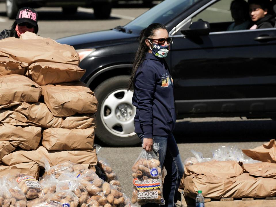 volunteer carries bags of potatoes at drive-thru potato handout