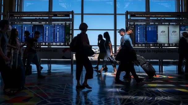 PHOTO: Travelers check their flight status at Ronald Regan Washington National Airport, July 11, 2022, in Arlington, Va.  (Nathan Howard/Getty Images)