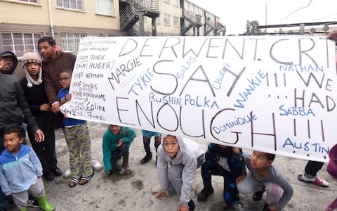 Residents of the Derwent Court flats hold a banner bearing the names of some - but not all - of the residents killed in gang wars since 2012 - Credit: Brenton Geach&nbsp;/The Telegraph&nbsp;