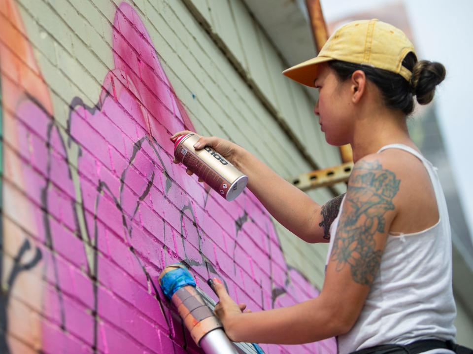 Artist candy Kuo paints a mural at The Cellar on Thursday, July 7, 2022.