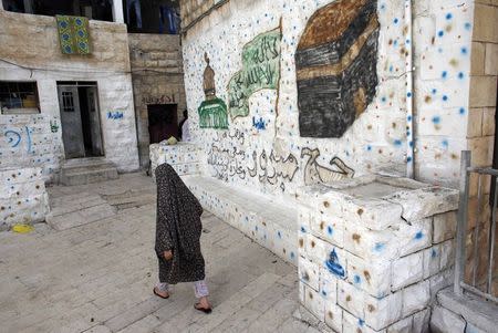 A Palestinian woman walks outside her home, next to a house (R) purchased by Jews, in the mostly Arab neighbourhood of Silwan in east Jerusalem October 20, 2014. REUTERS/Ronen Zvulun