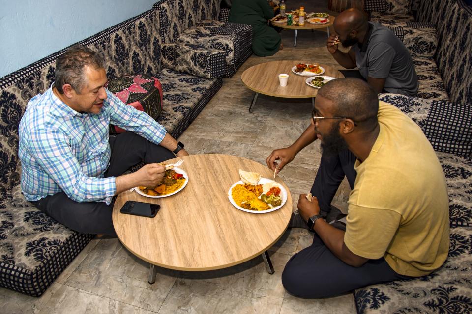 Bill Nazur, Abdiqani Mohamed and Mohamed Mohamed eat dinner while sitting on floor cushions at Mandi House in Tempe on April 25, 2022.