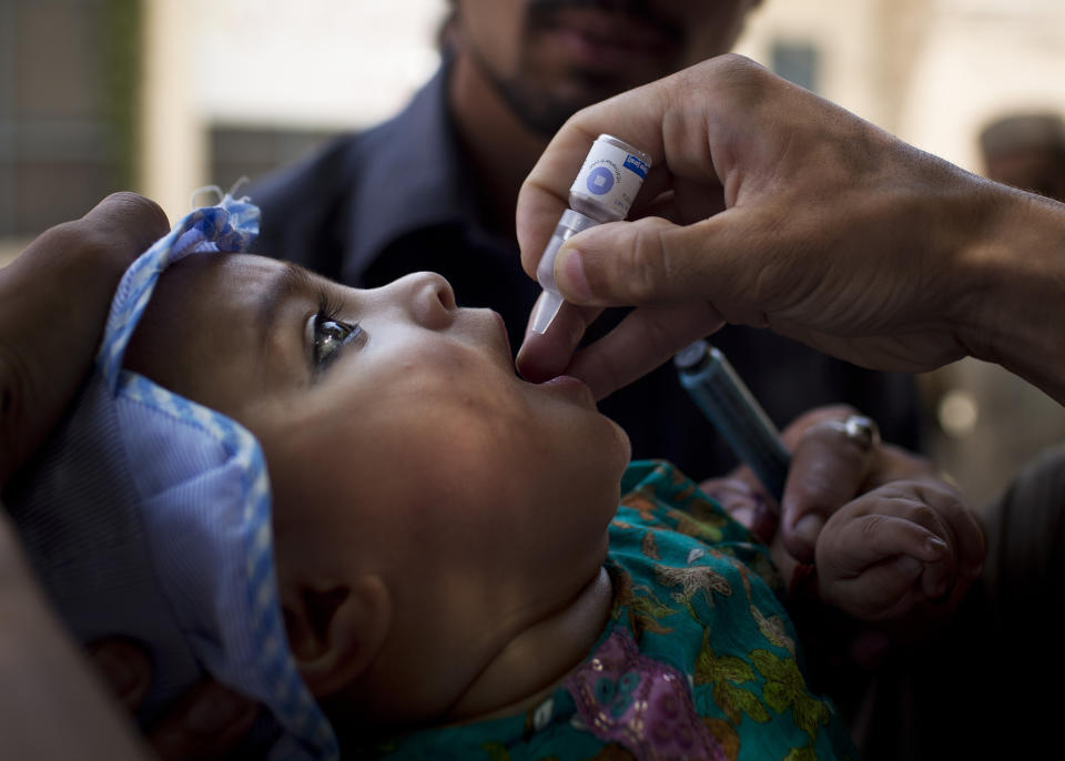 FILE - A child is administered a polio vaccination by a district health team worker outside a children's hospital in Peshawar, Pakistan on Wednesday, May 30, 2012. (AP Photo/Anja Niedringhaus, File)