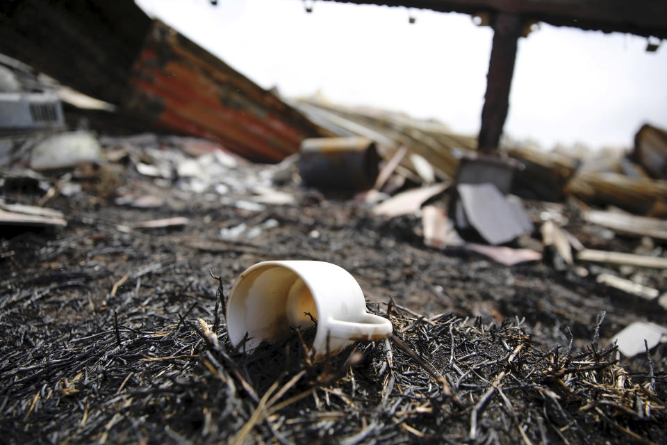 A coffee mug sits among the burnt remains of Joshua Kihe's home near Waimea, Hawaii, Wednesday, Aug. 4, 2021. The home was scorched by the state's largest ever wildfire. (AP Photo/Caleb Jones)