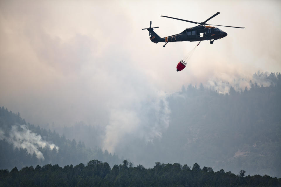 This photo taken Aug. 6, 2018, shows a helicopters returning from performing an air operation on the Coal Hollow Fire near U.S. Highway 6. An Idaho prisoner sent to help fight a wildfire in Utah raped a woman who also was working to support firefighters, prosecutors said Tuesday, Sept. 4, 2018. The woman had rejected several advances from Ruben Hernandez, 27, in the days before the Aug. 29 assault at the base camp, Sanpete County attorney Kevin Daniels said. Hernandez has been charged with felony rape. (Evan Cobb/The Daily Herald via AP)