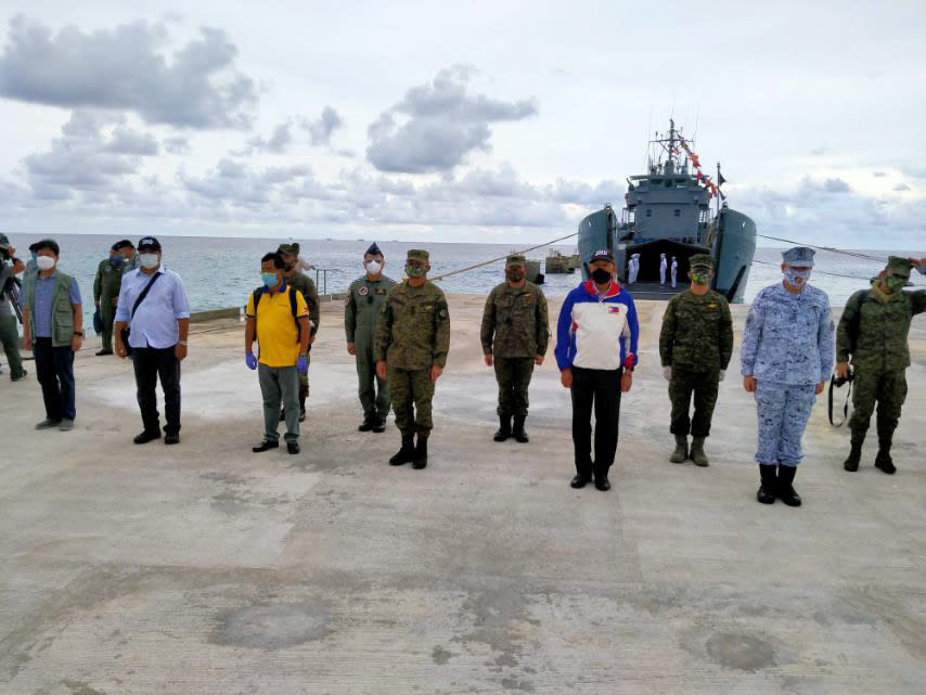 In this handout photo provided by the Department of National Defense PAS, Defense Secretary Delfin Lorenzana, 4th from right, stands with other military and local officials during a short ceremony at the newly built beach rampway at the Philippine-claimed island of Pag-asa, also known as Thitu, in the disputed South China Sea on Tuesday June 9, 2020. The Philippine defense chief and top military officials flew to a disputed island in the South China Sea Tuesday to inaugurate a beach rampway built to allow the "full-blast" development of the far-flung territory but would likely infuriate China. (Department of National Defense PAS via AP)