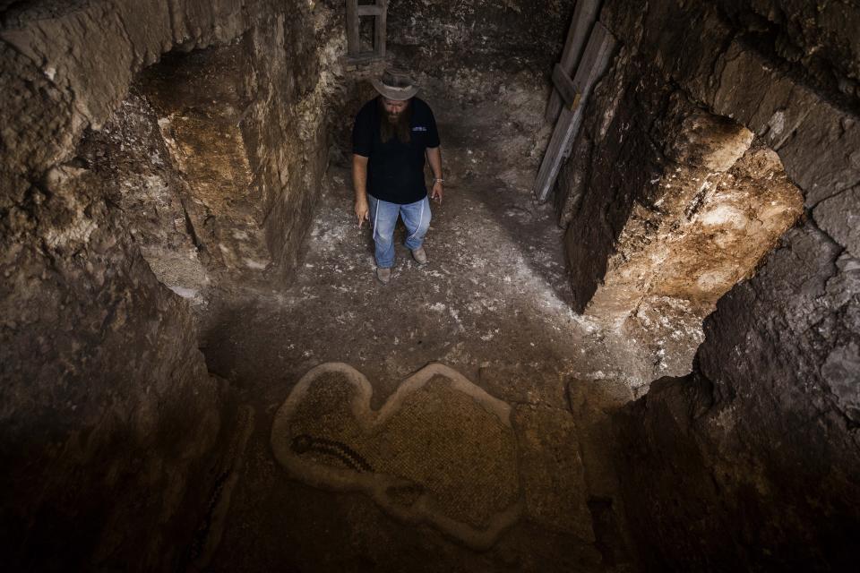 An Israeli archaeologist Binyamin Storchan from the Israel Antiquities Authority, shows an ancient crypt in the remains of an ancient church that was recently uncovered in Beit Shemesh, near Jerusalem. Wednesday, Oct. 23, 2019. Israeli archaeologists have revealed an elaborately decorated Byzantine church dedicated to an anonymous martyr that was recently uncovered near Jerusalem. The Israel Antiquities Authority showcased some of the finds from the nearly 1,500-year-old structure on Wednesday after three years of excavations. (AP Photo/Tsafrir Abayov)