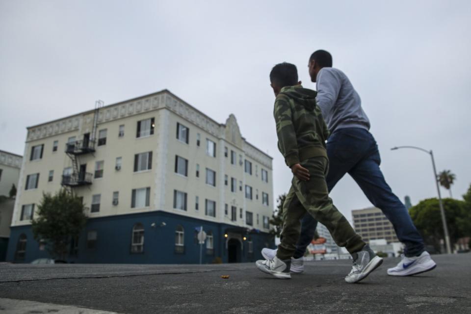 A father and his young son walk along a city street