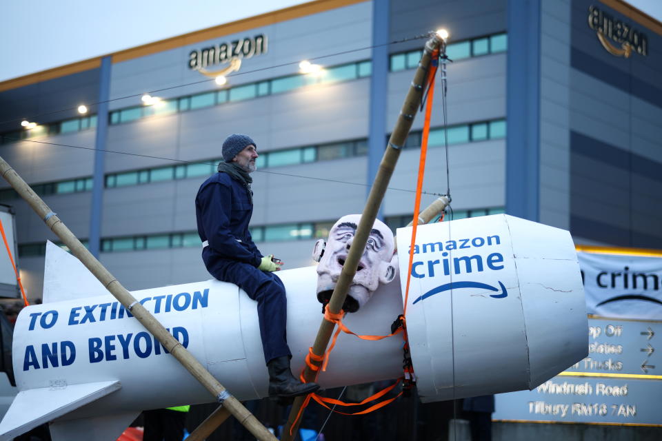 A man sits on a fake rocket as Extinction Rebellion activists block an entrance to an Amazon fulfilment centre in Tilbury, Essex, Britain, November 26, 2021. REUTERS/Henry Nicholls