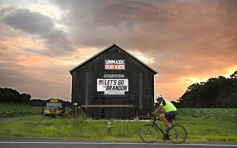 A bicyclist rides past a barn with political banner on it