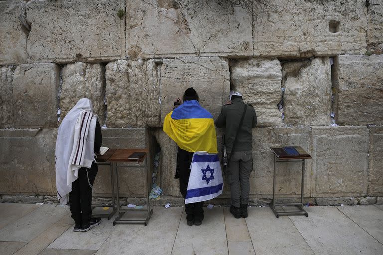 Un judío ultraortodoxo envuelto en banderas nacionales de Ucrania e Israel reza en el Muro Occidental, el lugar más sagrado donde los judíos pueden rezar en la Ciudad Vieja de Jerusalén, el viernes 4 de marzo de 2022