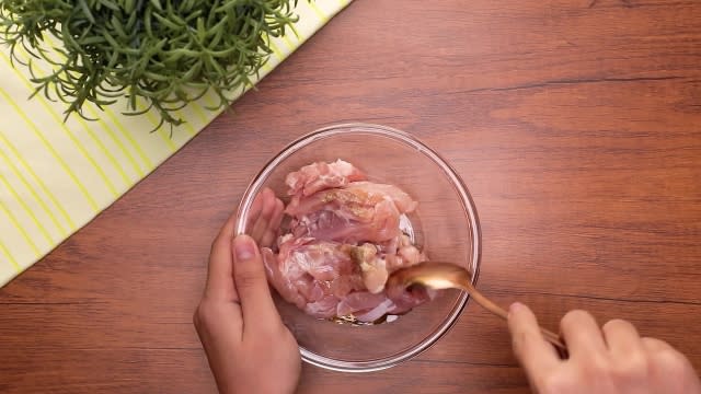 Mixing chicken and marinade in a bowl with a spoon