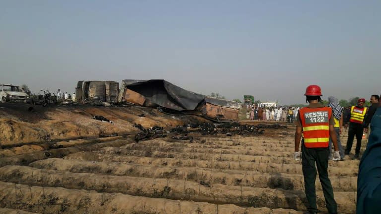 Rescue workers gather around the burnt remains of an oil tanker which caught fire following an accident on a highway near the town of Ahmedpur East, some 670 kilometres (416 miles) from Islamabad on June 25, 2017