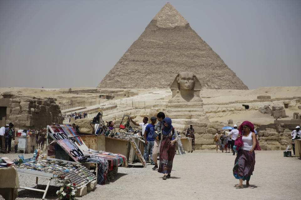 In this photo taken Friday, May 31, 2013, tourists walk past vendors at the Giza Pyramids in Giza, Egypt. A statement by Egypt’s Antiquities’ Ministry Saturday, June 1, 2013 says a U.S. Embassy security warning sent to citizens to be extra cautious for their safety in the area of the Pyramids is baseless. Earlier in the week, the U.S. Embassy in Cairo sent a message to its citizens warning them to “elevate their situational awareness when traveling to the Pyramids” due to a “lack of visible security or police” in the area. (AP Photo/Hiro Komae)