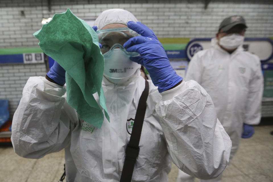 A workers wearing protective gears adjusts her glasses while she prepares to spray disinfectant as a precaution against the coronavirus at a subway station in Seoul, South Korea, Friday, Feb. 21, 2020. South Korea on Friday declared a "special management zone" around a southeastern city where a surging viral outbreak, largely linked to a church in Daegu, threatens to overwhelm the region's health system. (AP Photo/Ahn Young-joon)