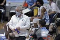 North Carolina trainer Doug Halverson works the bench area during the team's NCAA college basketball game against Syracuse in Chapel Hill, N.C., Tuesday, Jan. 12, 2021. The coronavirus pandemic has added another constantly shifting layer to what they do. The last 10 months have turned into a complicated juggling act of tending to athletes' day-to-day needs while dealing with the intricacies that come with trying to play sports and keeping everyone safe — themselves included — in a pandemic. (AP Photo/Gerry Broome)