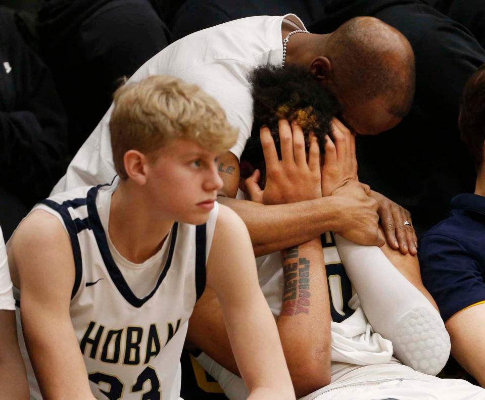 Archbishop Hoban's Jonas Nichols, right, is consoled by his trainer Aaron Ashburn as he sits next to teammate Joey Hardman after he was taken out in the final seconds of a Division I regional final at Copley on Saturday. St. Edward won 63-46. [Karen Schiely/Beacon Journal]