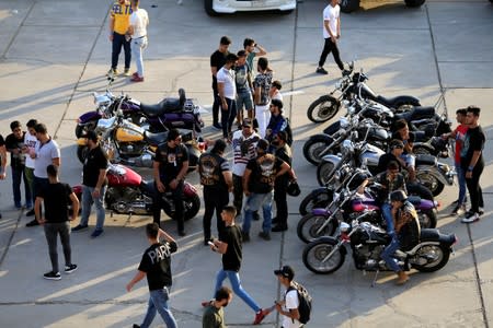 Young men attend a car and motorbike show outside the closed Hall of Shaab Stadium in Baghdad