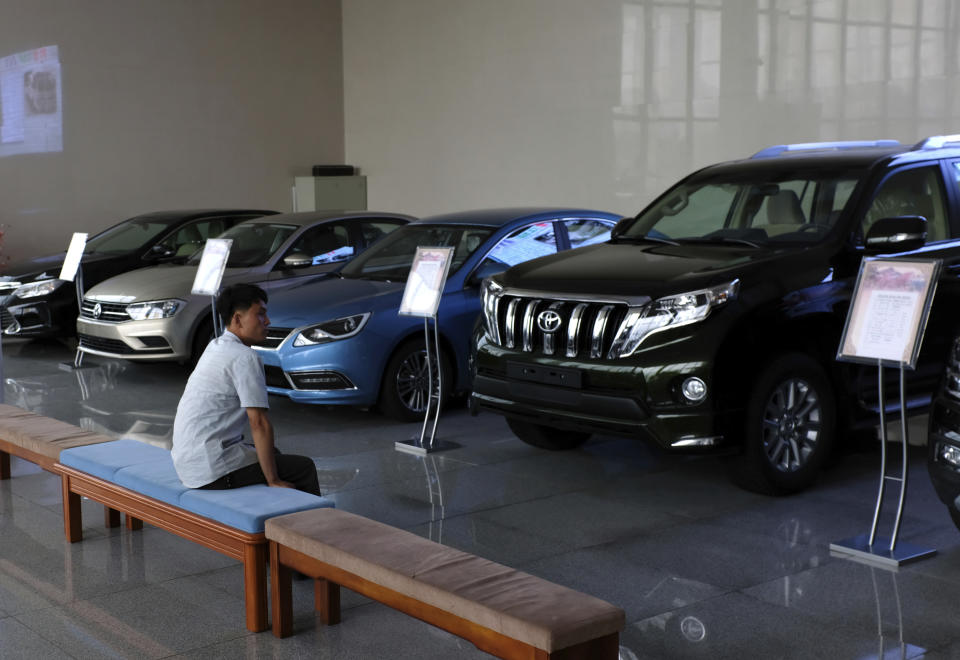 In this July 26, 2018 photo, a man sits at a showroom that sells imported cars in Pyongyang, North Korea. Twenty years after his father almost bargained them away for a pair of nuclear reactors, North Korean leader Kim Jong Un has his nuclear weapons - and a nation still plagued by chronic blackouts. But years of sanctions have spurred the North to cobble together a creative smorgasbord of alternative resources, some off the official grid and some flat-out illegal. (AP Photo/Dita Alangkara)