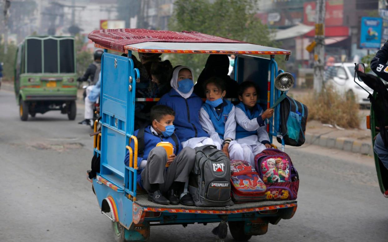 Students in Pakistan, which is currently facing a second wave of the virus, get a lift to school - KM Chaudary/AP