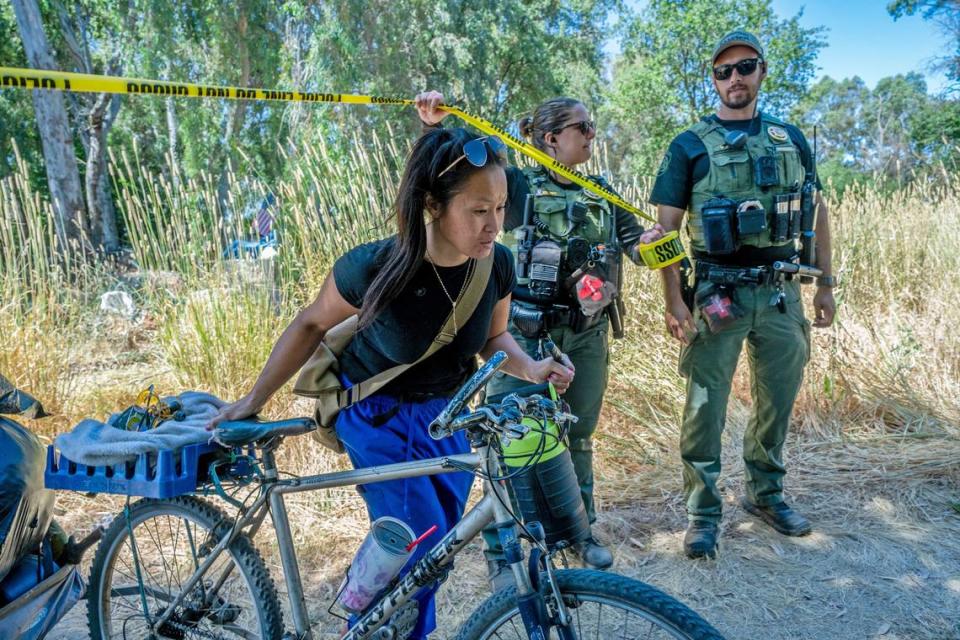 Sacramento County Park Rangers hold police tape as Chaming Vang, 38, uses a bicycle cart to move some of her belongings during a sweep of a homeless encampment in Rio Linda on Monday. “We are being shoved out again, they don’t have a place for us to go, so where am I supposed to go? They gave us 48 hours to move. I work and the thing is I can’t do all this in 48 hours,” said Vang. “I’ve been here for ten years now.”