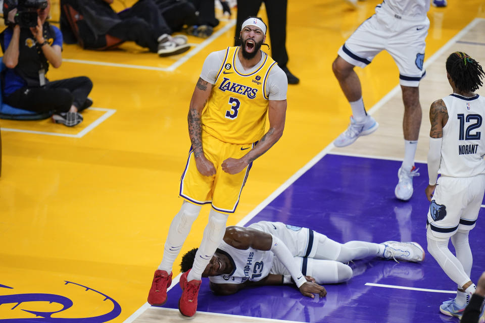 Los Angeles Lakers' Anthony Davis (3) celebrates his dunk as Memphis Grizzlies' Jaren Jackson Jr. (13) falls to the court during the second half in Game 6 of a first-round NBA basketball playoff series Friday, April 28, 2023, in Los Angeles. (AP Photo/Jae C. Hong)