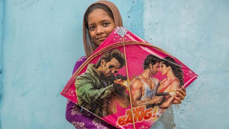 Kite maker Sheikh Kayamat, 14, shows the kite he is making.  For a SEWA-trained home-based worker using special tables and chairs, the average wage is 100 rupees per day for 1,000 kites. 