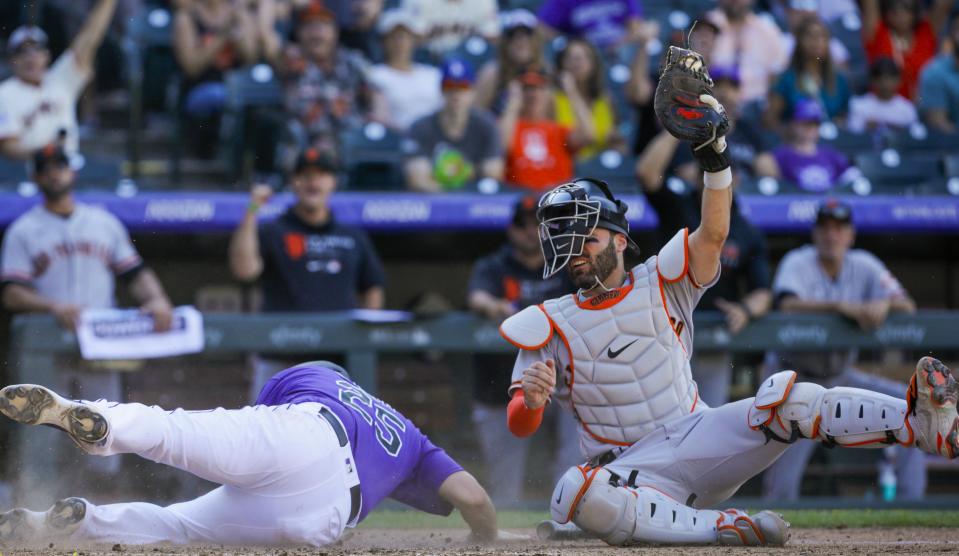 San Francisco Giants catcher Curt Casali, right, holds up the ball as Colorado Rockies' C.J. Cron slides safely home in seventh inning of an baseball game in Denver, Sunday, Sept. 26, 2021. (AP Photo/Joe Mahoney)