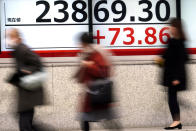 People walk past an electronic stock board showing Japan's Nikkei 225 index at a securities firm in Tokyo Friday, Jan. 24, 2020. Shares are mostly higher in quiet trading as China closes down for its week-long Lunar New Year festival. (AP Photo/Eugene Hoshiko)
