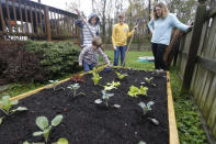 Stephanie Owens, right, looks over the garden with her son, Cole, left, Reid, top left, and Lucas, top center, as they tend to it at their home Wednesday March 25 , 2020, in Glen Allen, Va. Owens is a pharmacist who has had to continue to go to work, but has been able to spend more time with her kids because they are home from school . One of the activities that they have done is planting the garden. (AP Photo/Steve Helber)