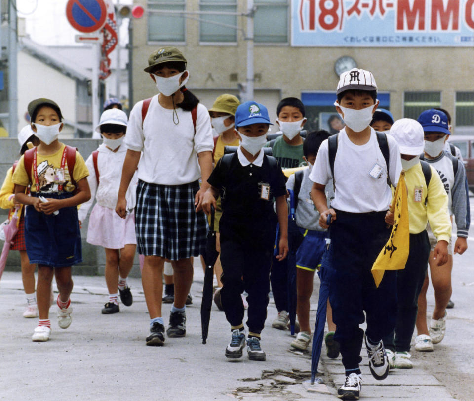 FILE - In this June 6, 1991, file photo, Shimabara school children, wearing masks and hats to protect themselves from falling ash from Mount Unzen, go to school in Shimabara. Volcanic activities continued and the death toll from Monday's eruption was at in the dozens. (AP Photo/Koji Sasahara, File)