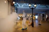 Volunteers in protective suits disinfect a shopping complex in Wuhan