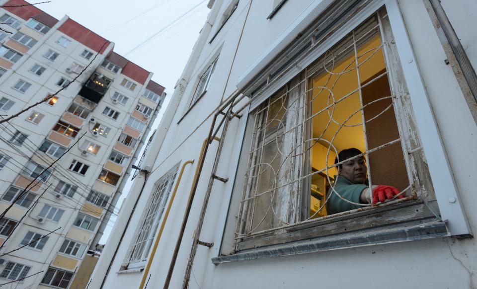 A woman removes broken glass next to a damaged multi-storey apartment block following a reported drone attack in Voronezh (REUTERS)